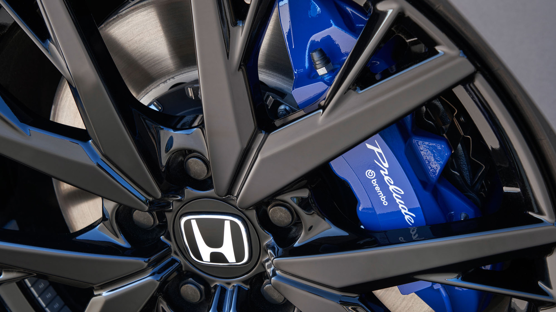 A blue Prelude brembo brake caliper behind a black Honda alloy wheel.