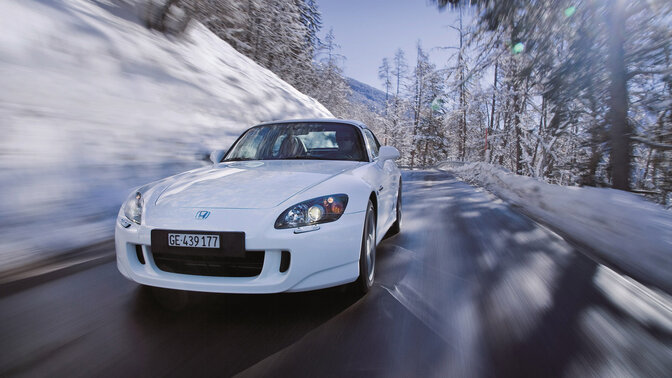 Side facing Honda e:Ny1 in a forest location with a lookout to the city.