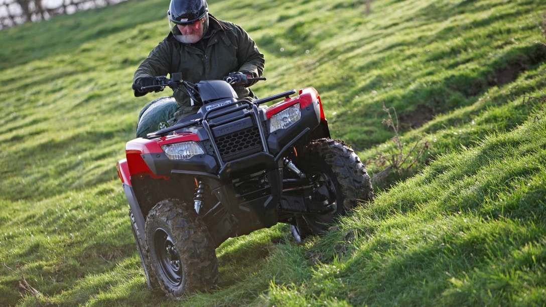 Front three-quarter, right facing Fourtrax 420, being used by model, field location.