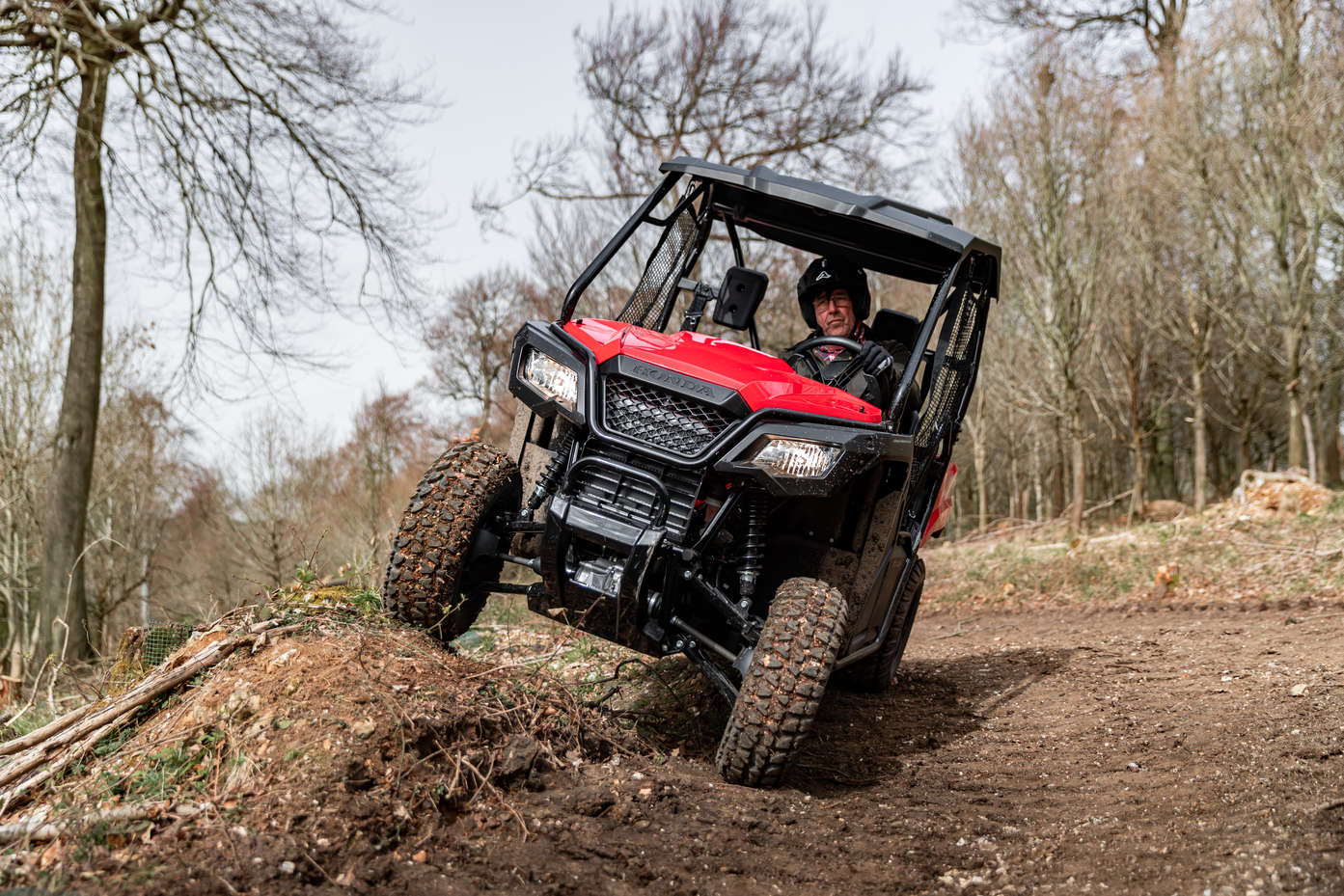 Picture of a Honda Pioneer 520 going offroad over a bump in a dirt track landscape