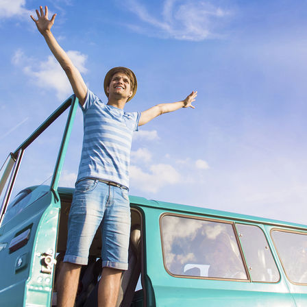 close up of a smiling man standing outside a blue car