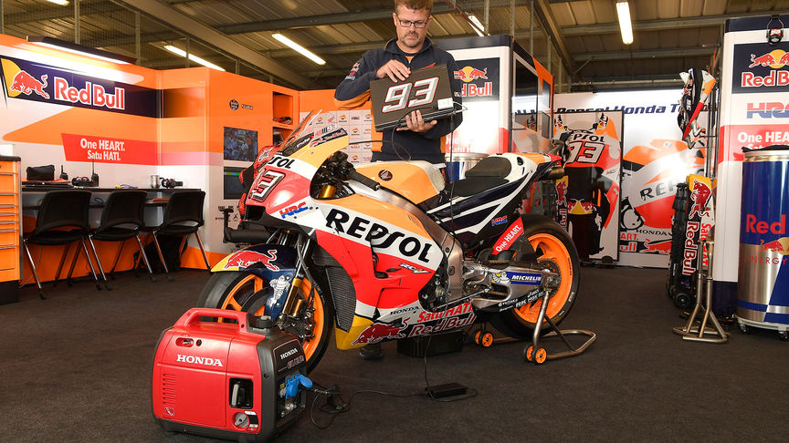 eu22i portable generator in repsol honda garage next to cbr125r motorbike and man holding laptop
