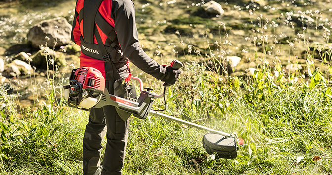 Man using a Honda brushcutter on grass