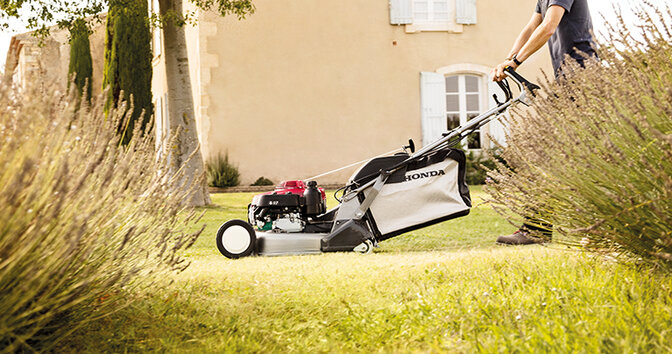Man using a Honda HRD lawnmower on grass