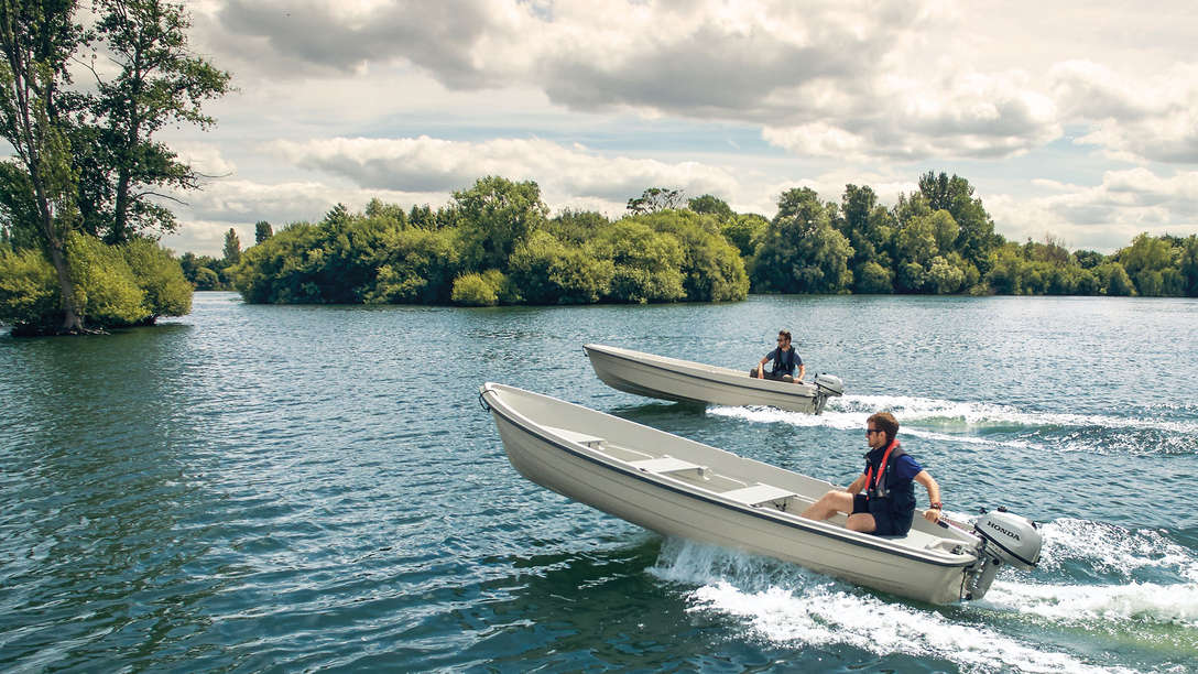 side angled view of two men steering boats on the water fitted with honda marine engines