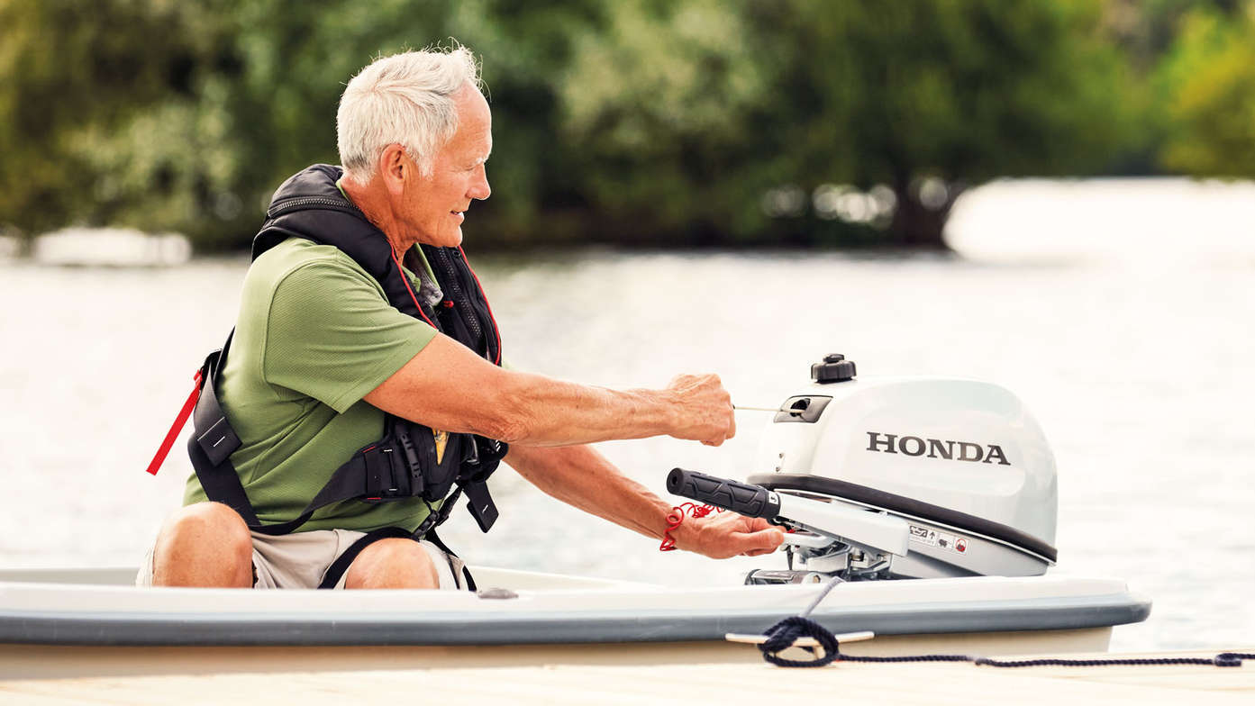 side view of old man operating honda boat motor