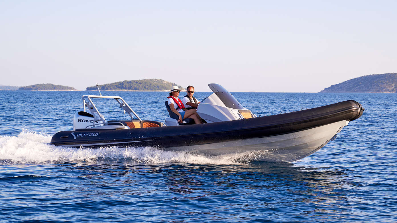 side view of people steering highfield boat on the water