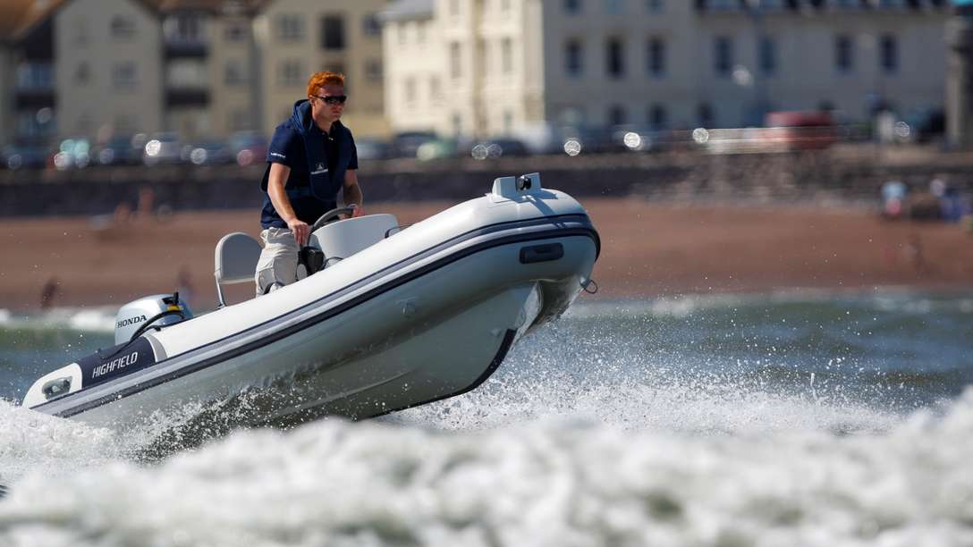 side angled view of a man standing on a highfield boat fitted with a honda outboard engine