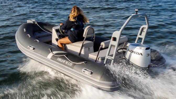 side angled view of a woman steering a highfield boat powered by a 30 horsepower honda outboard engine