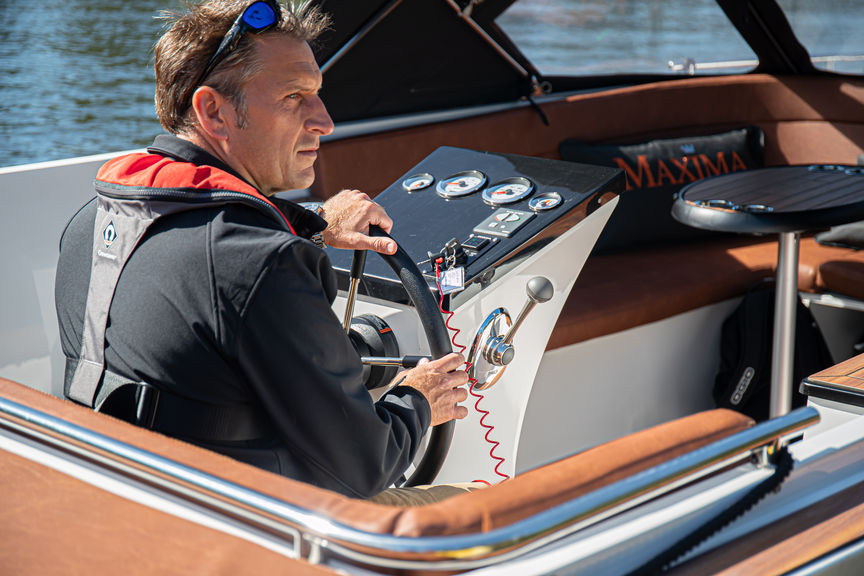 photo of man in life jacket steering maxima boat