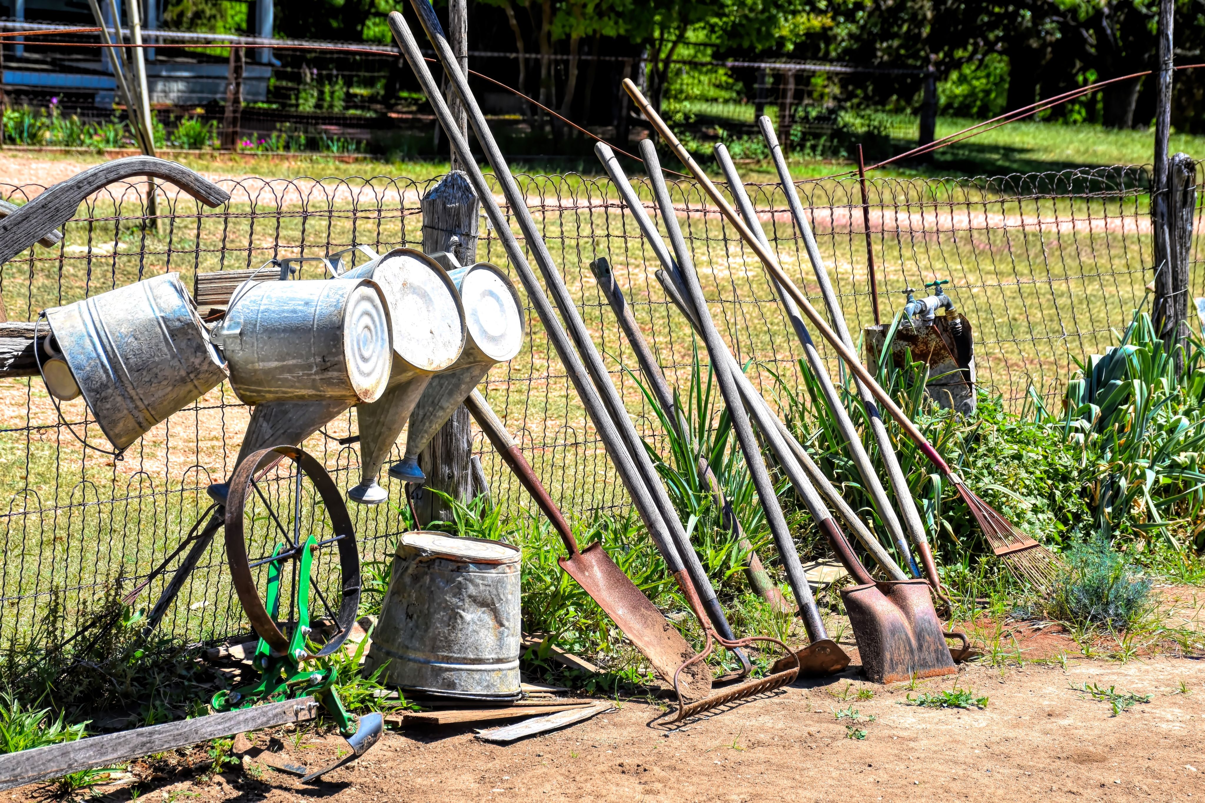 garden hoe and other garden tools sitting next to a fence